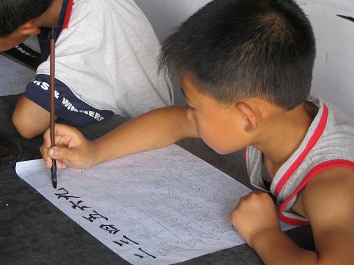 Chinese boy practicing his calligraphy in school