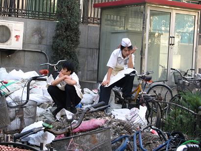 Sitting on a mound of garbage and bicycles, restaurant workers take a break